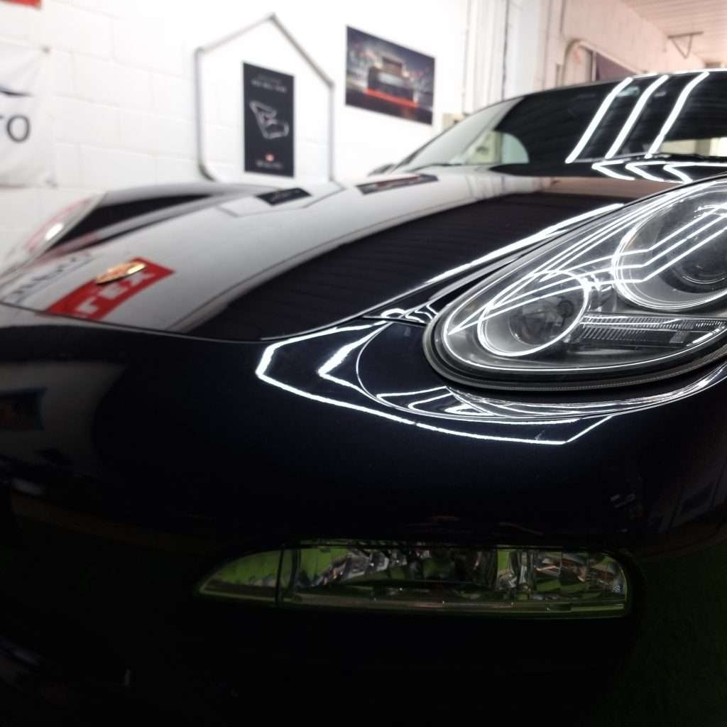 Close-up of glossy black paint and headlight after ceramic coating