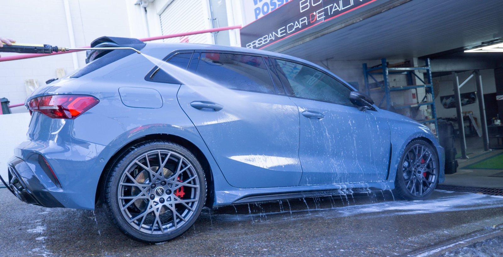 Blue Audi hatchback being hand washed outside the Brisbane Car Detailing Services workshop
