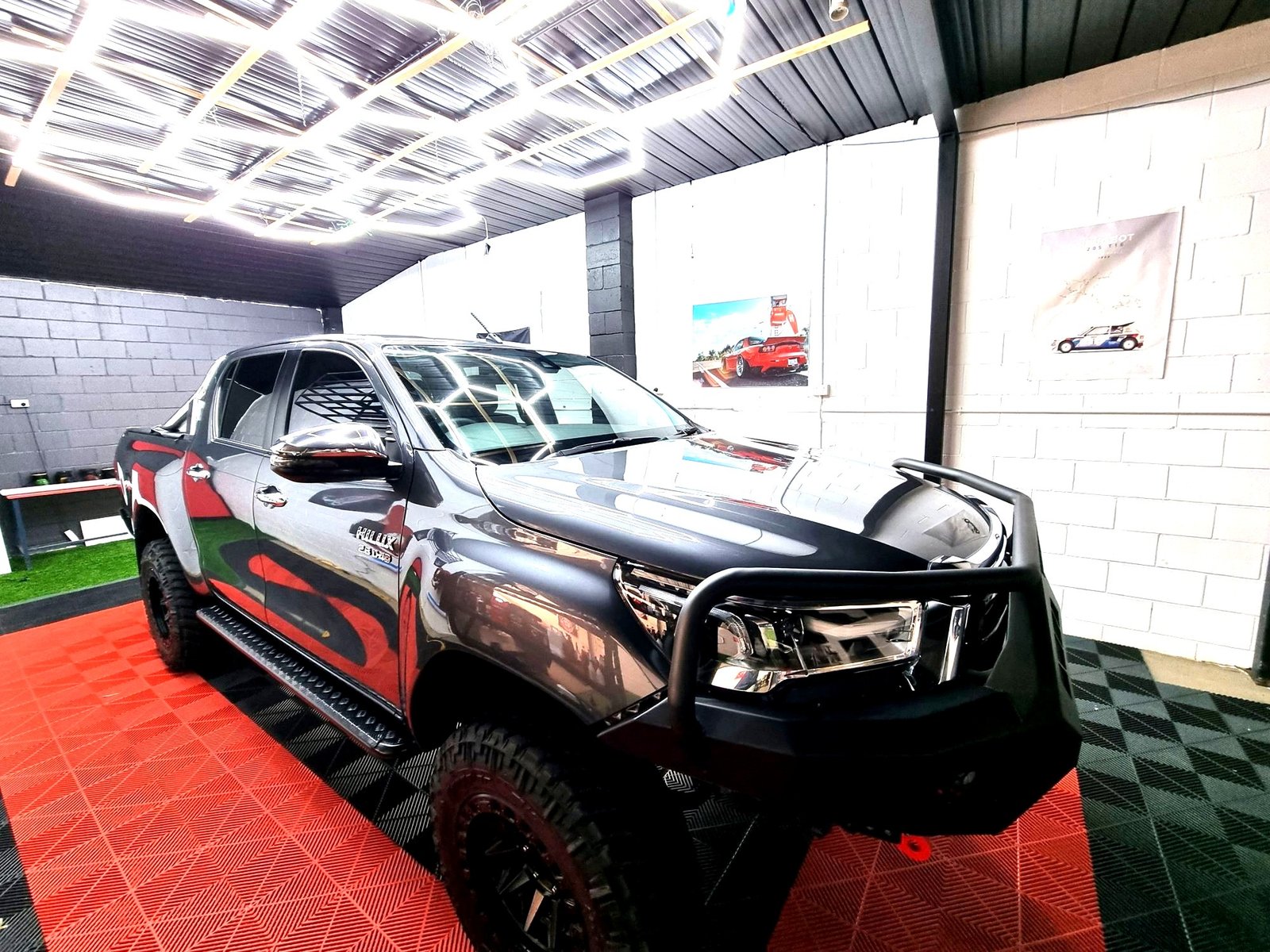 Corrected Toyota Hilux with deep gloss finish under the workshop's hexagon light rig