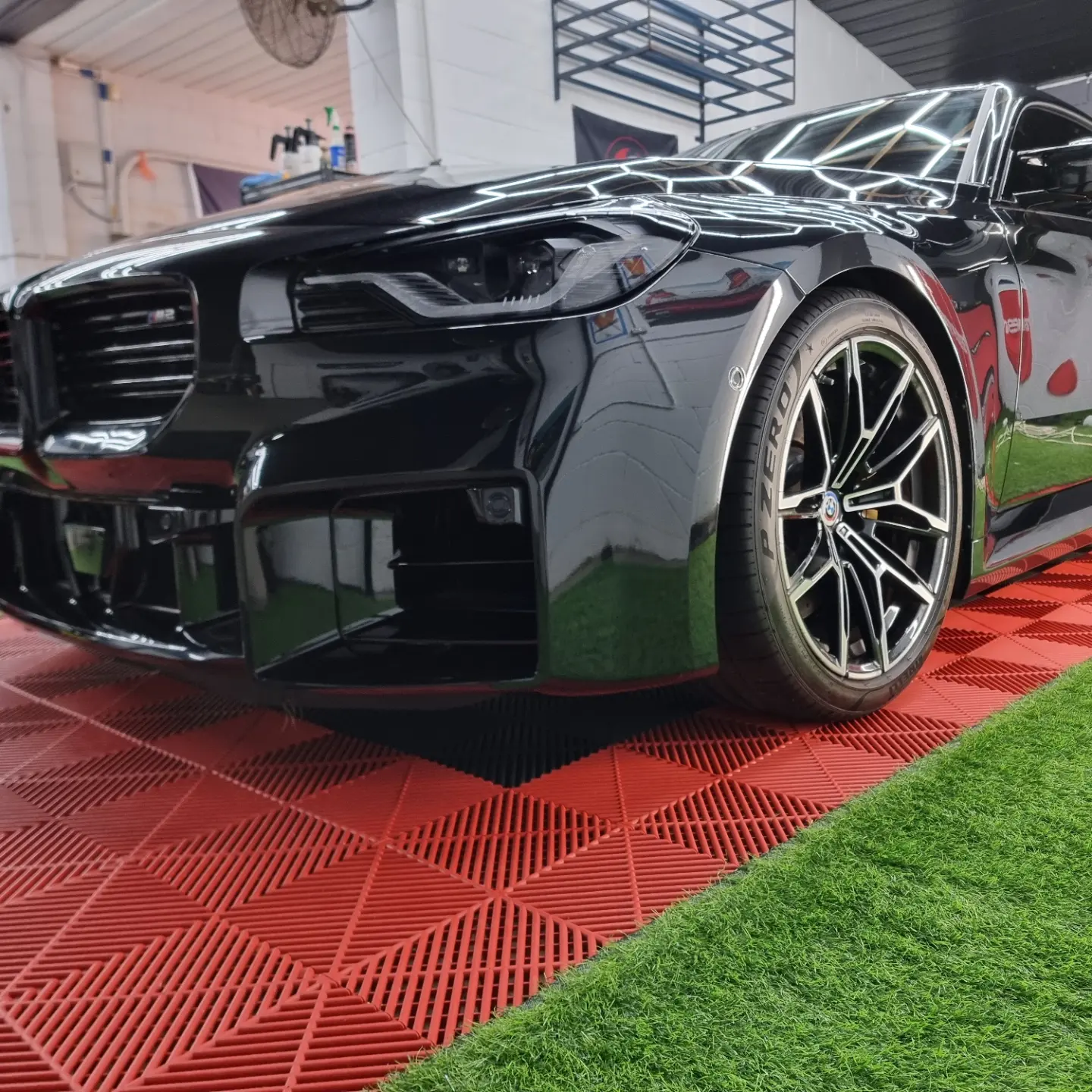 Black BMW M2 with fresh graphene ceramic coating reflecting the workshop's hexagon light rig