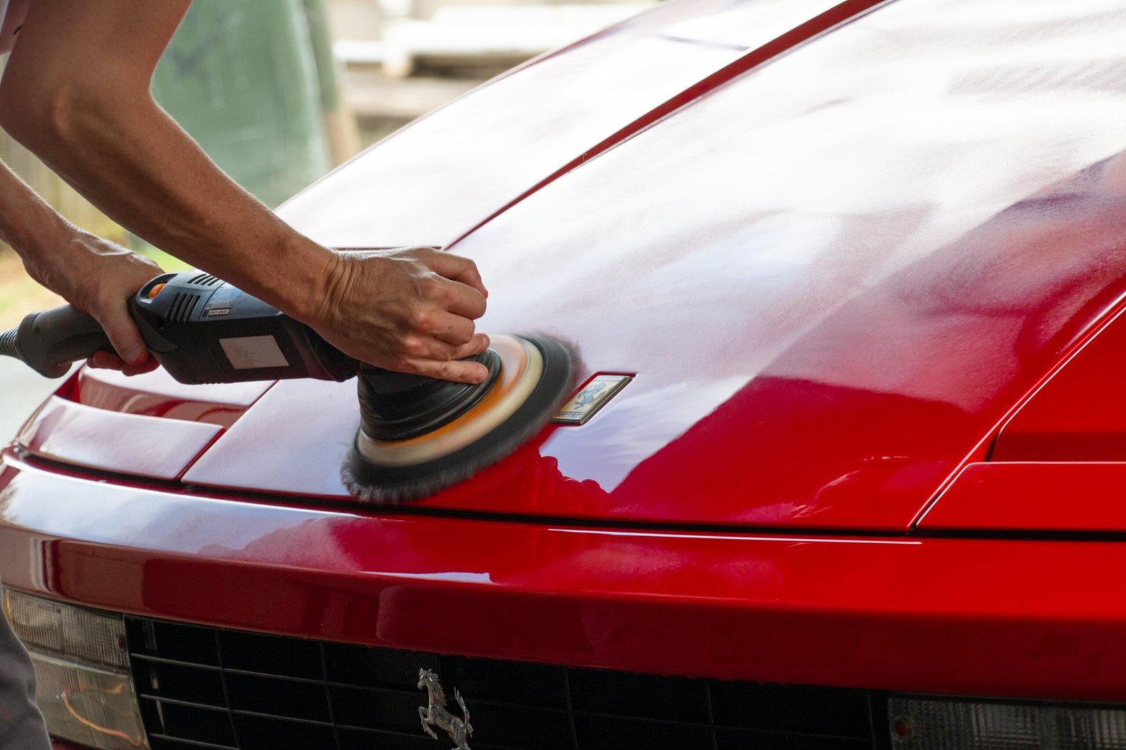 Technician machine-polishing a classic Ferrari's paintwork during a paint correction stage